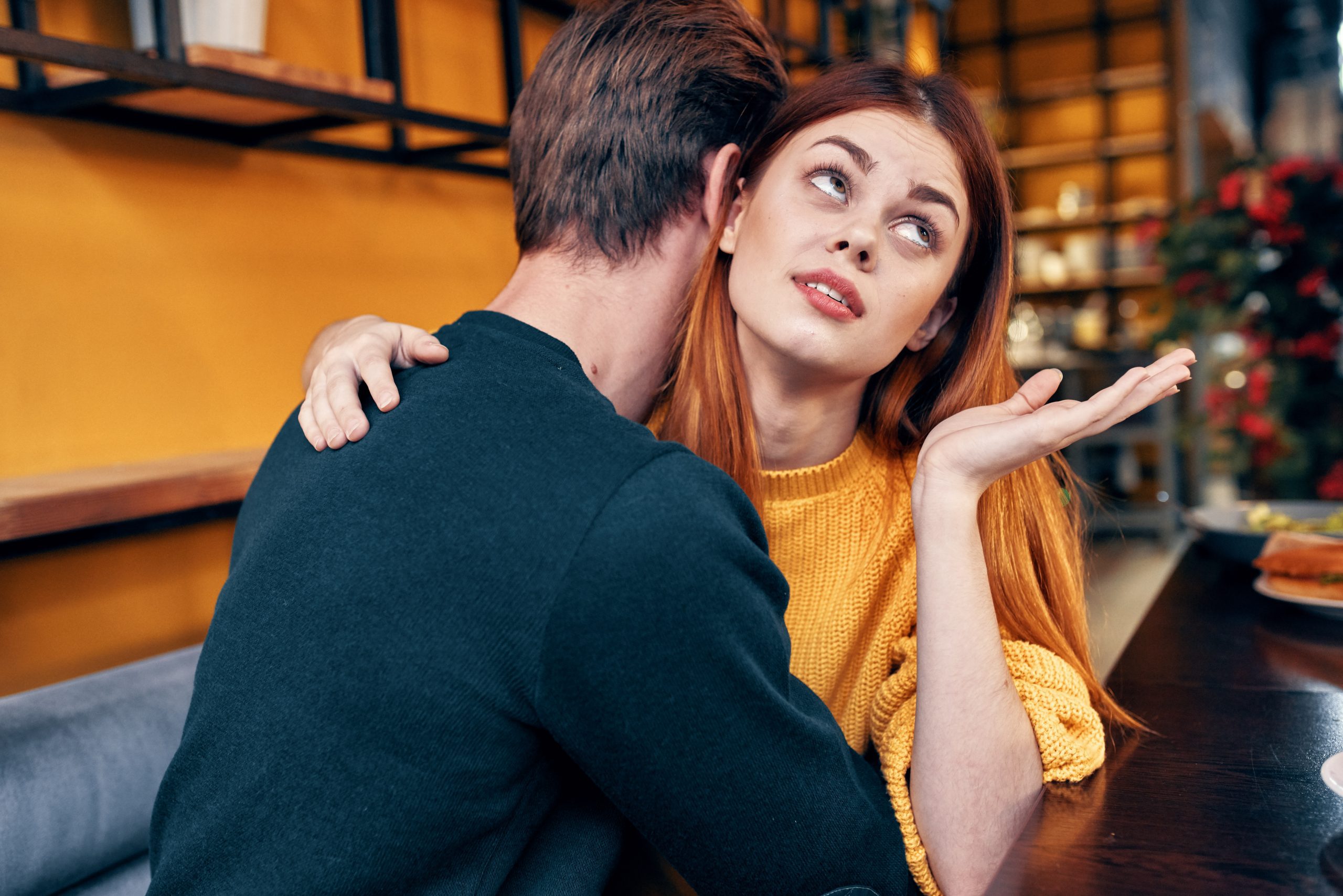 Why Your Girlfriend Starts Drama Out Of Nowhere - And How To Stay Calm And In Control 22 Why Your Girlfriend Starts Drama Out Of Nowhere - Romantic Woman Hugs A Young Man In A Sweater At A Table In A Cafe Interior A Couple In Love. High Quality Photo
